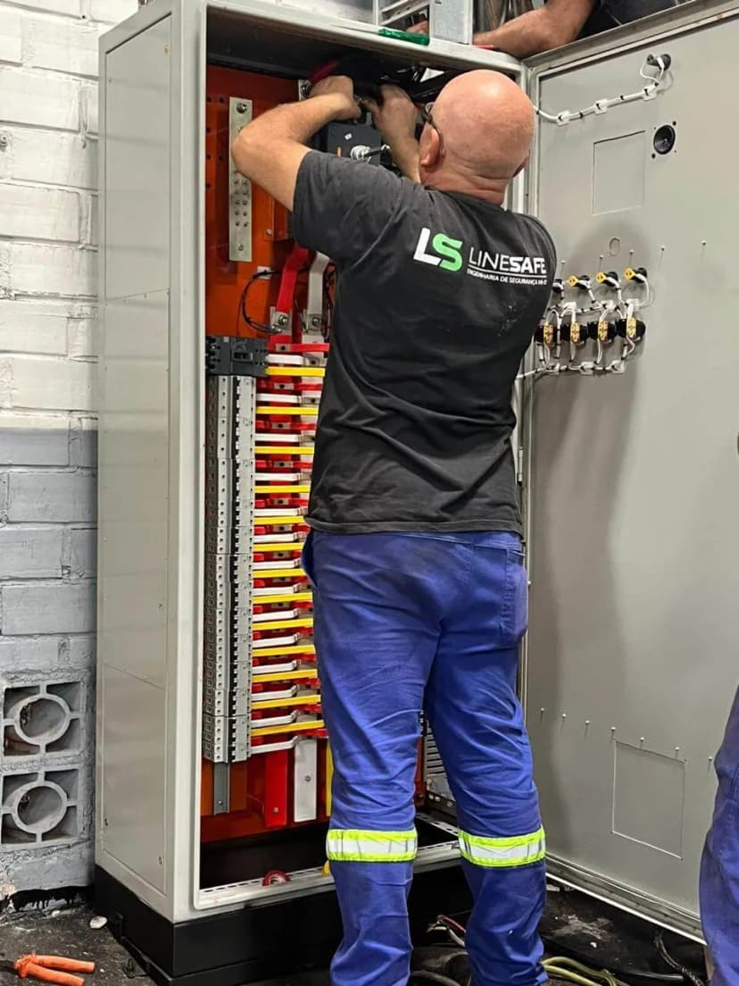 Profissional da LineSafe na montagem de um quadro de distribuição com barramentos e disjuntores